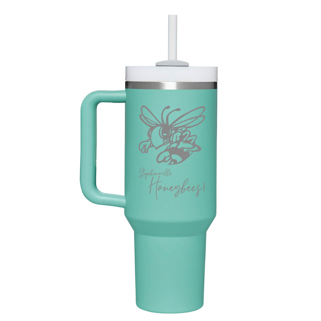 This is an insulated engraved stainless steel tumbler with a handle. The engraved image is the Stephenville Honeybees logo. The cup is eucalyptus in color. 