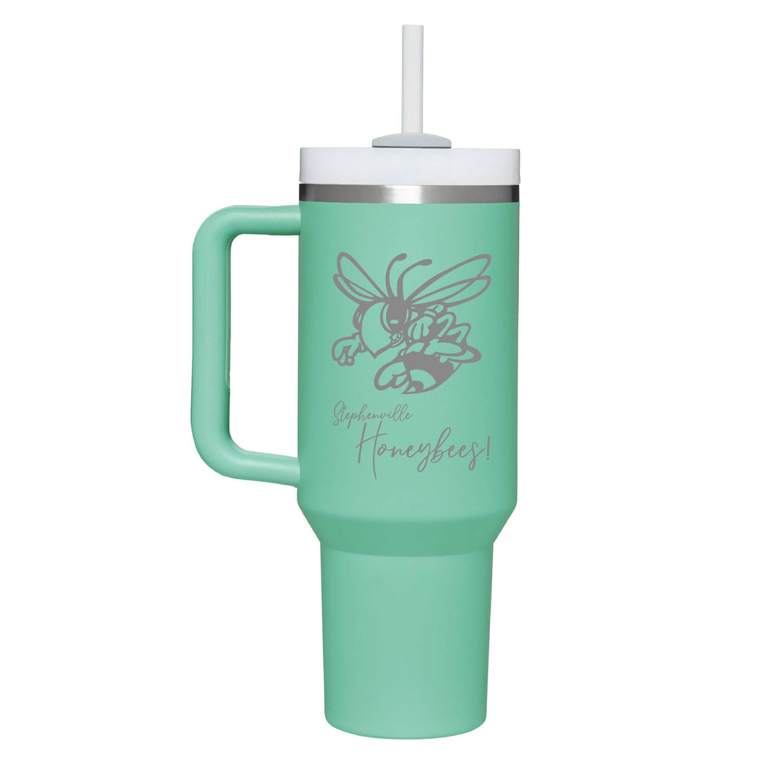 This is an insulated engraved stainless steel tumbler with a handle. The engraved image is the Stephenville Honeybees logo. The cup is teal in color. 